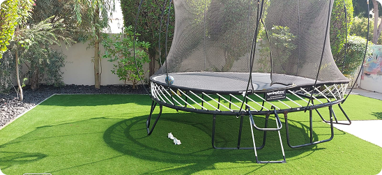 Play area with trampoline and green artificial grass